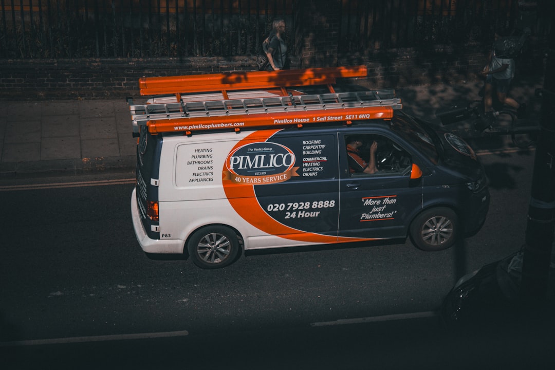 a-white-van-with-an-orange-and-black-advertisement-on-the-side-jfqhyulxqb0