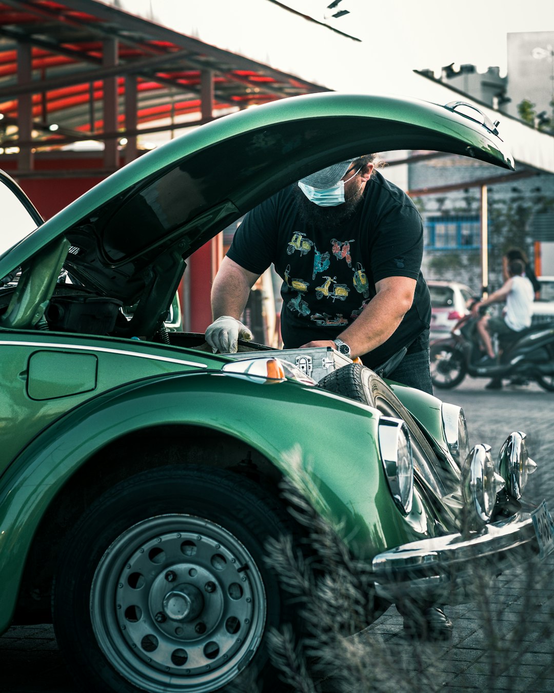 man-in-black-t-shirt-and-white-pants-standing-beside-green-car-8tb8yud-z0s